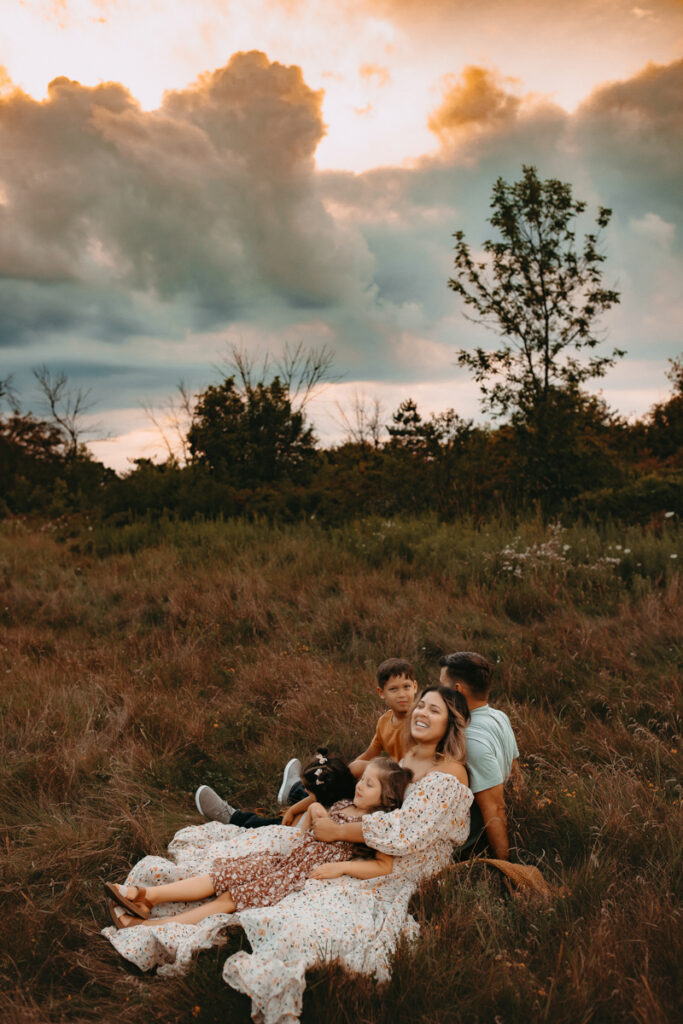 Family of 5 sitting in an Oak Creek, WI field at sunset. 