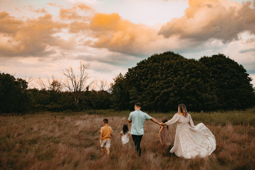 Family of five wearing their sunday best walking through a Wisconsin field at sunset. 
